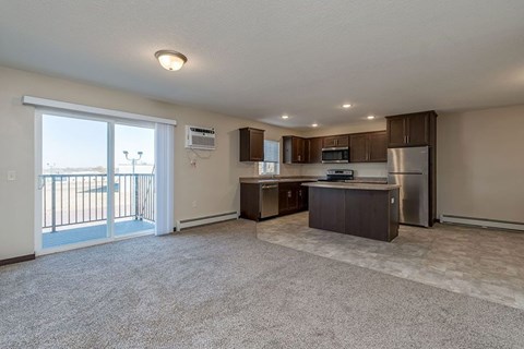 A spacious living room with a kitchenette and a balcony.