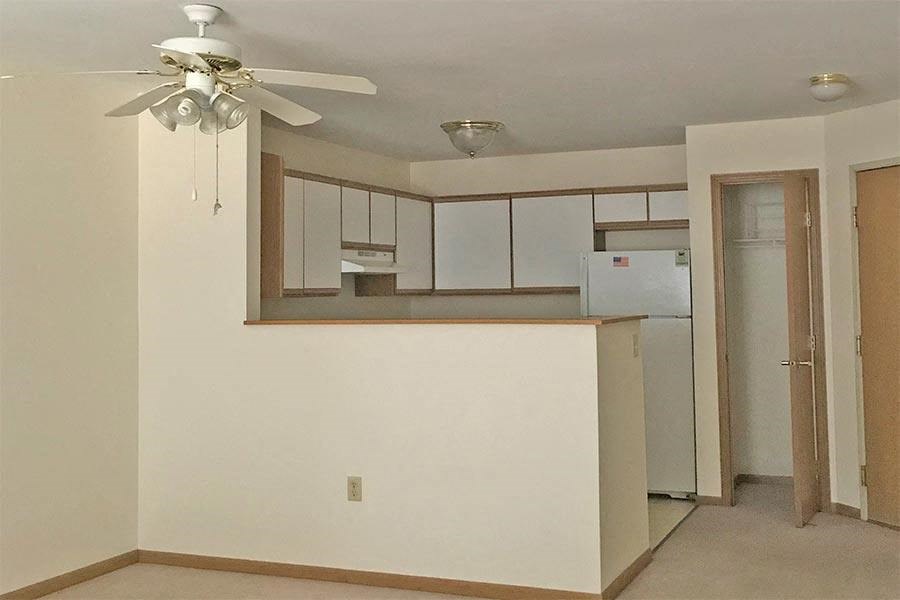 an empty kitchen with a ceiling fan and a refrigerator