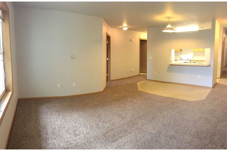 an empty living room with a carpeted floor