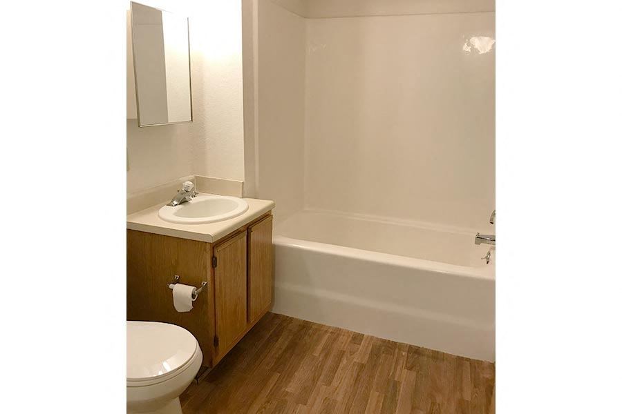 A white sink is on a wooden cabinet next to a white toilet.