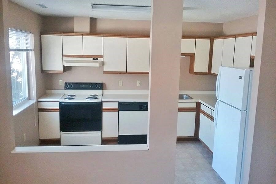 an empty kitchen with a stove and a refrigerator