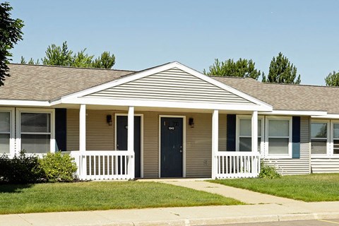 a tan house with a porch and a blue door