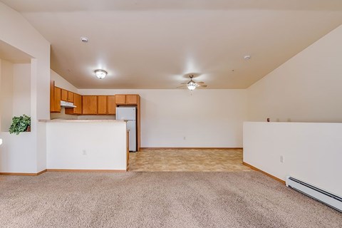 A spacious room with a carpeted floor and a ceiling fan.