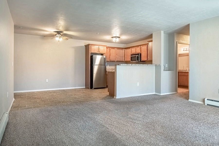 an empty living room and kitchen with a refrigerator