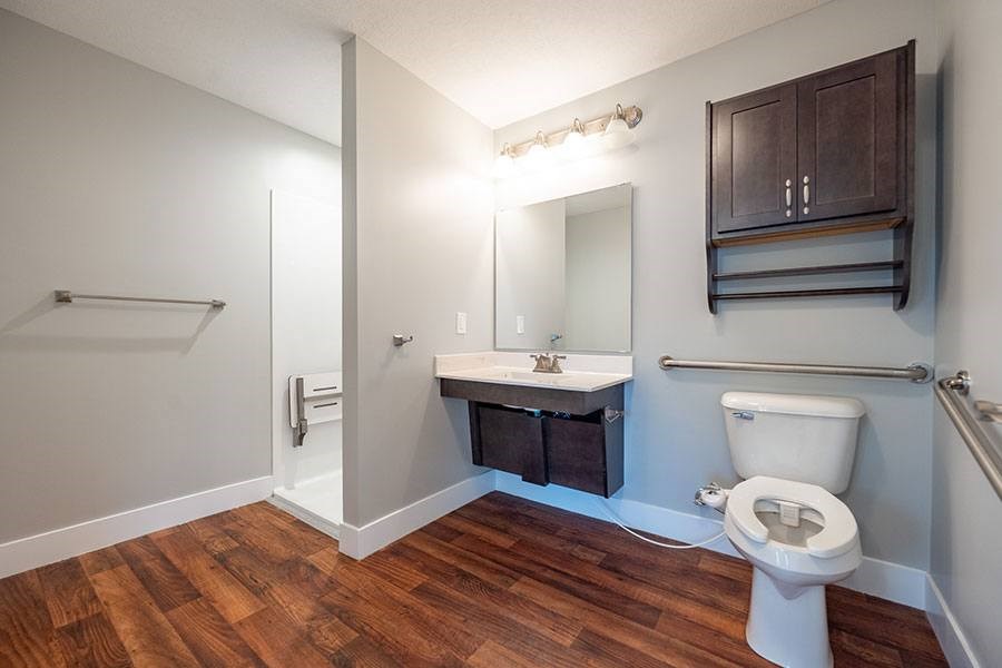 A bathroom with a toilet, sink, and mirror.