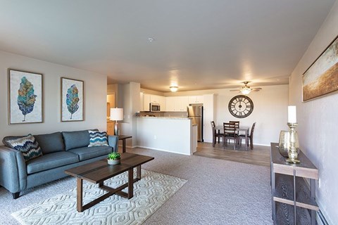 A living room with a grey couch, a coffee table, and a clock on the wall.