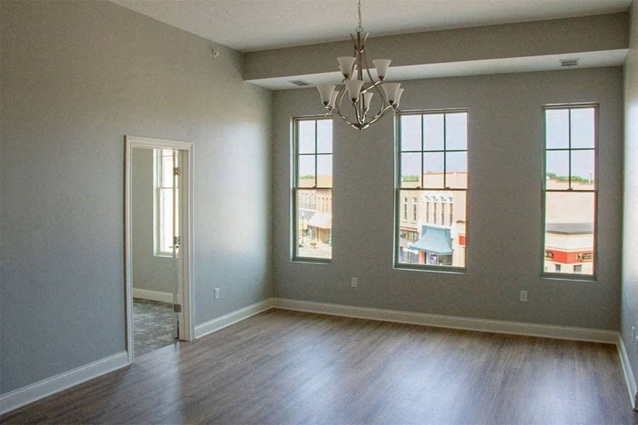 an empty living room with wood floors and a chandelier