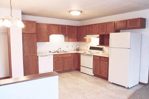 A kitchen with white appliances and wooden cabinets.