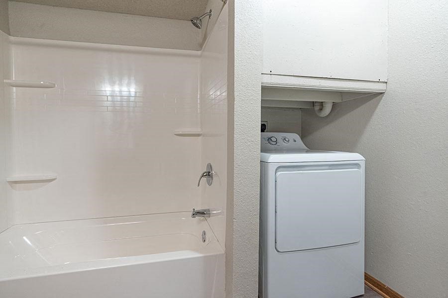 a white bathroom with a washing machine and a tub