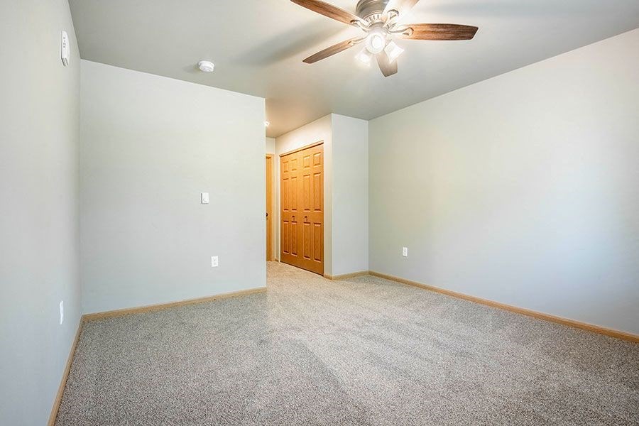 a empty living room with a ceiling fan and a closet