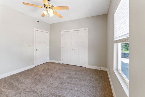 A room with a ceiling fan and carpeted floor.