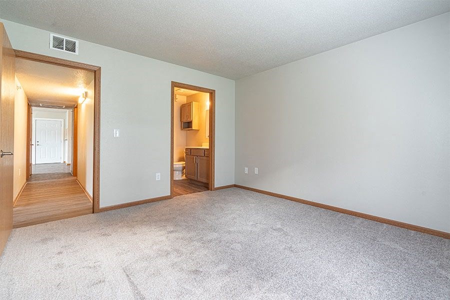 an empty living room with carpet and a door to a bathroom