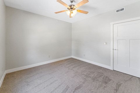 A room with a ceiling fan and carpeted floor.