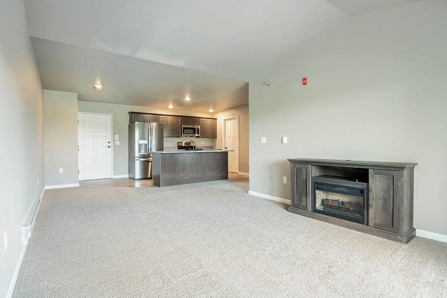 an empty living room with a fireplace and a kitchen