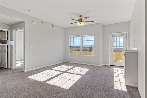 A spacious room with a ceiling fan and large windows.