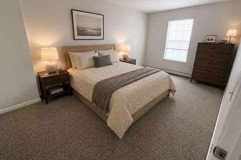 A bedroom with a large bed, two lamps, and a picture on the wall.
