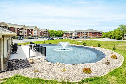 a fountain in the middle of a pond in front of a building