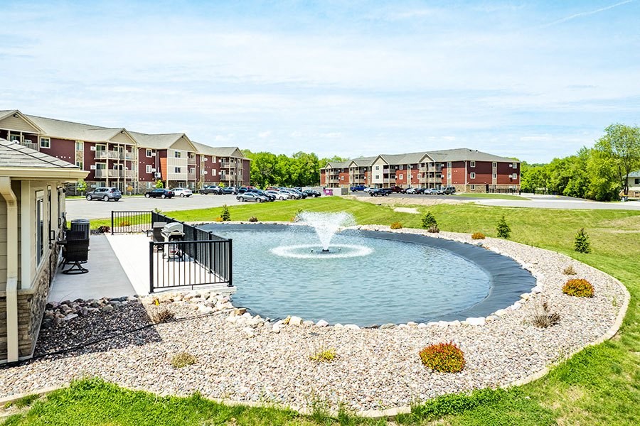 a fountain in the middle of a pond in front of a building