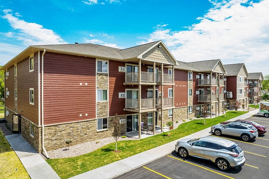 an apartment building with cars parked in a parking lot