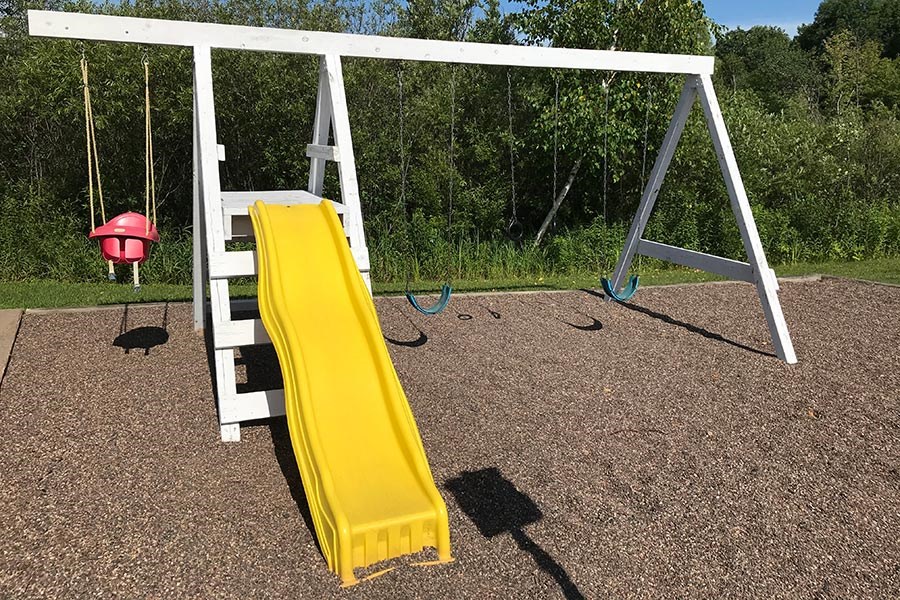 a swing set with a yellow slide on it
