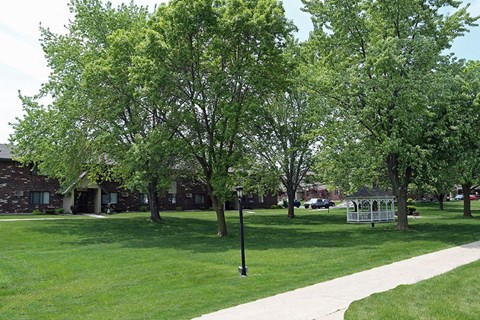 a park with trees and a gazebo in the grass