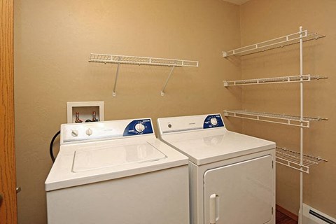 two washer and dryers in a room with shelves