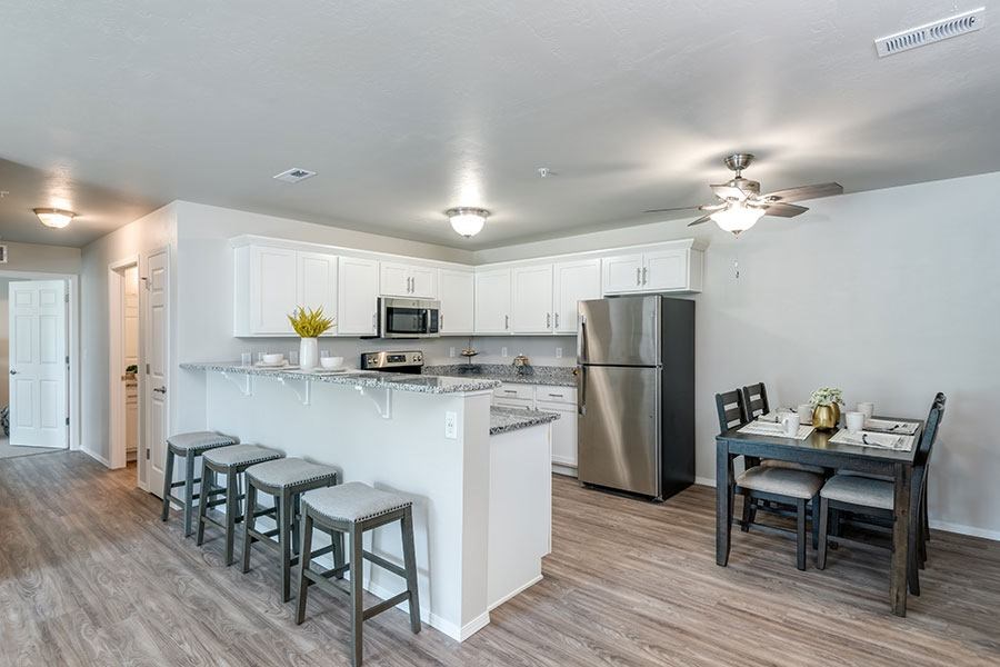 A kitchen with white cabinets and a wooden table.