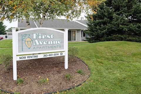 a sign for first avenue apartments in front of a house