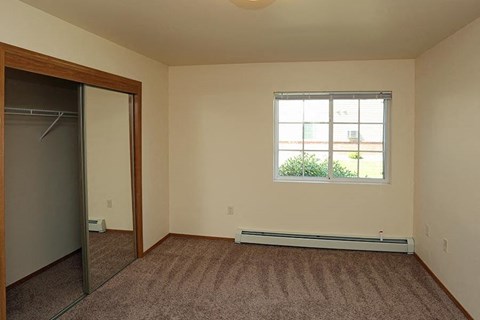 an empty room with a window and a closet