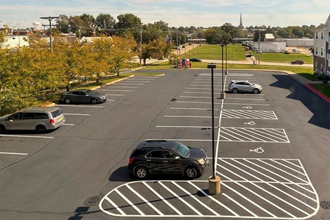 A parking lot with cars and a striped handicap spot.