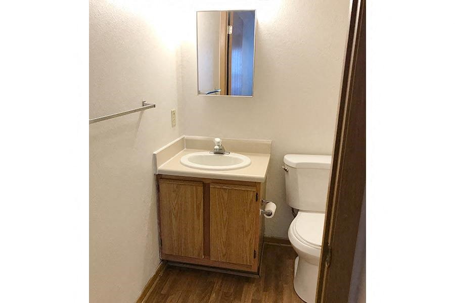 A small bathroom with a sink, toilet and mirror.