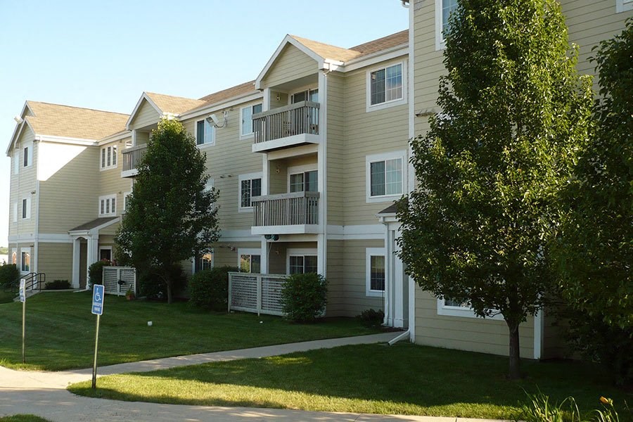 an apartment building with a lawn and trees