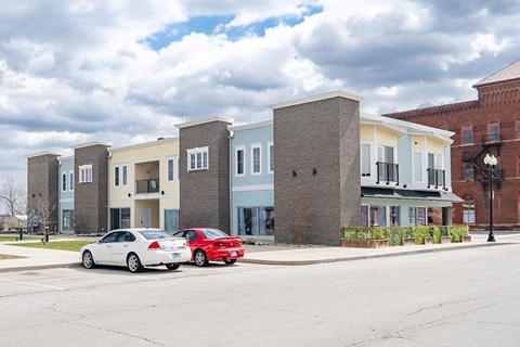 A row of townhouses with cars parked in front.