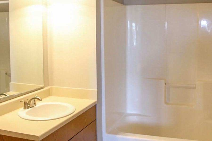 A white sink is on a counter next to a white shower.