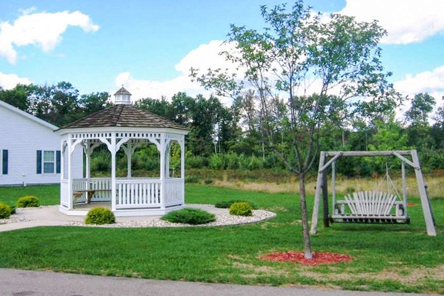 a white gazebo in a yard with two benches