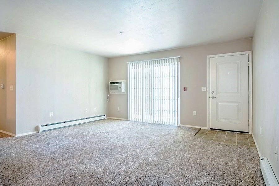 an empty living room with a white door and a window