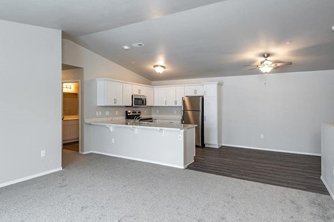 an empty living room and kitchen with a refrigerator