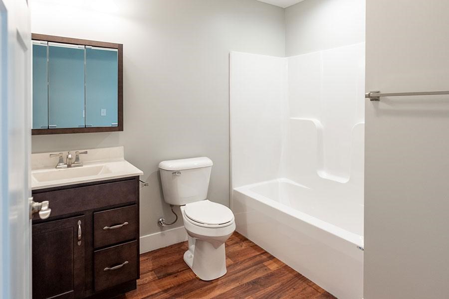 A white toilet sits in a bathroom next to a sink and a bathtub.