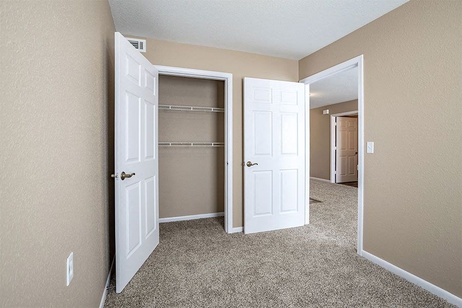 an empty bedroom with two closets and two doors