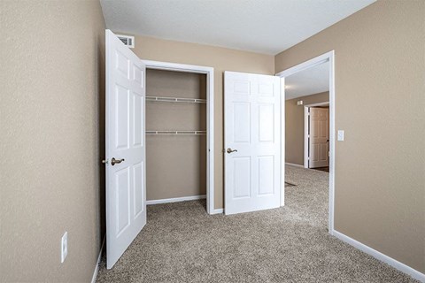an empty bedroom with two closets and two doors