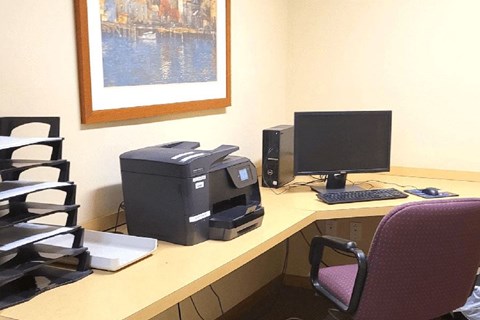A desk with a computer, monitor, and printer.