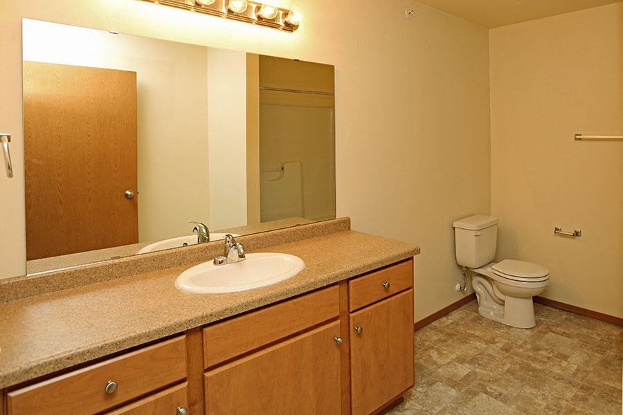 A bathroom with a sink, mirror, toilet and a door.