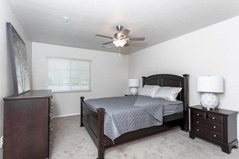 A bedroom with a bed, nightstand, and dresser.