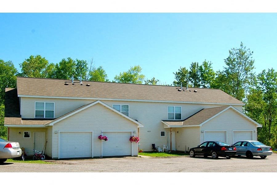 A two-story house with a garage and a car parked in front.