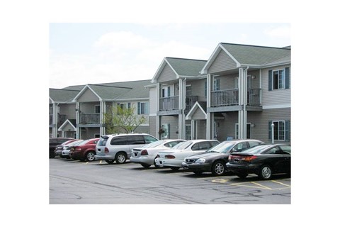 A parking lot with cars and apartment buildings in the background.