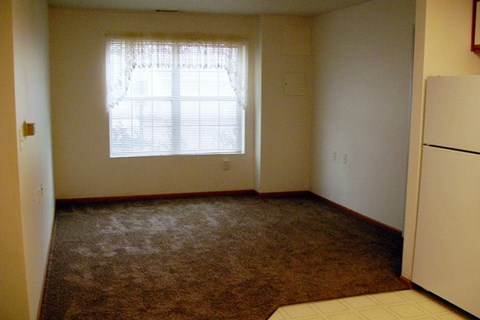 A room with a carpeted floor and a window with blinds.