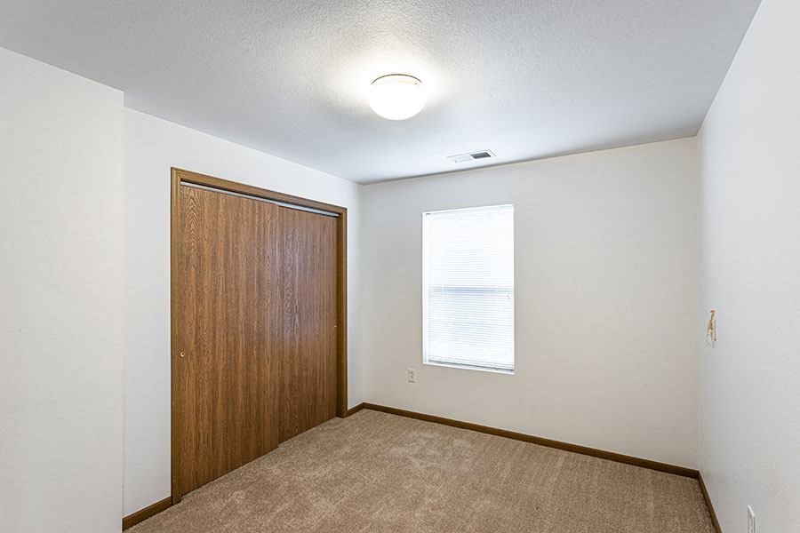 A room with a brown door and a window with blinds.