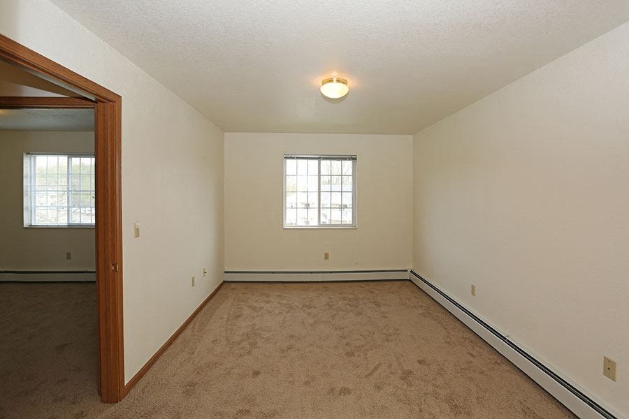 an empty living room with a mirror and carpet