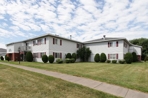 A white house with red shutters and a grey roof.