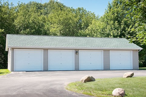 a white garage with blue doors and a green roof